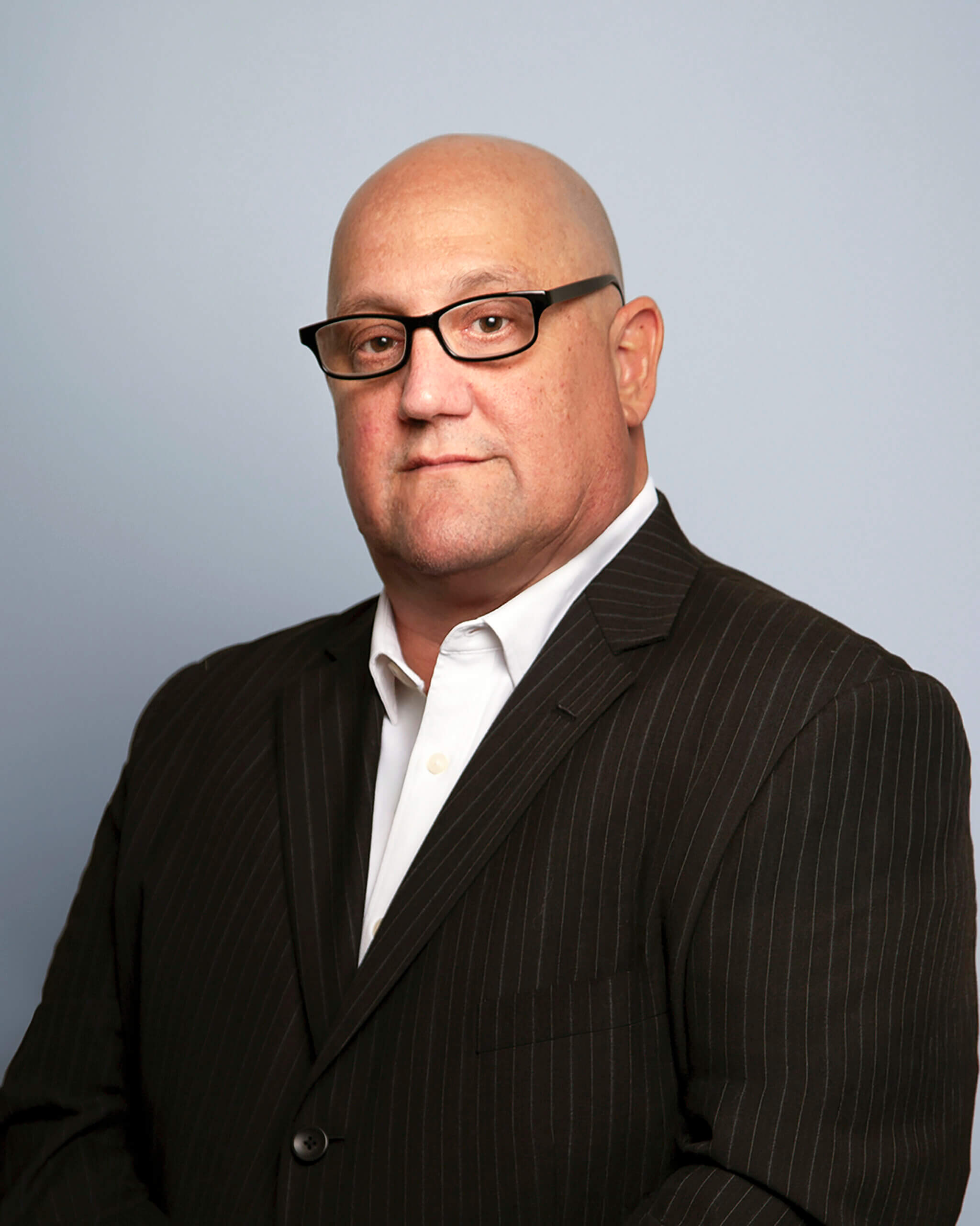 Scott Kuepferle – RNGD leadership headshot of Scott Kuepferle, in a pinstripe suit and white shirt, posed with a professional expression against a gray background.