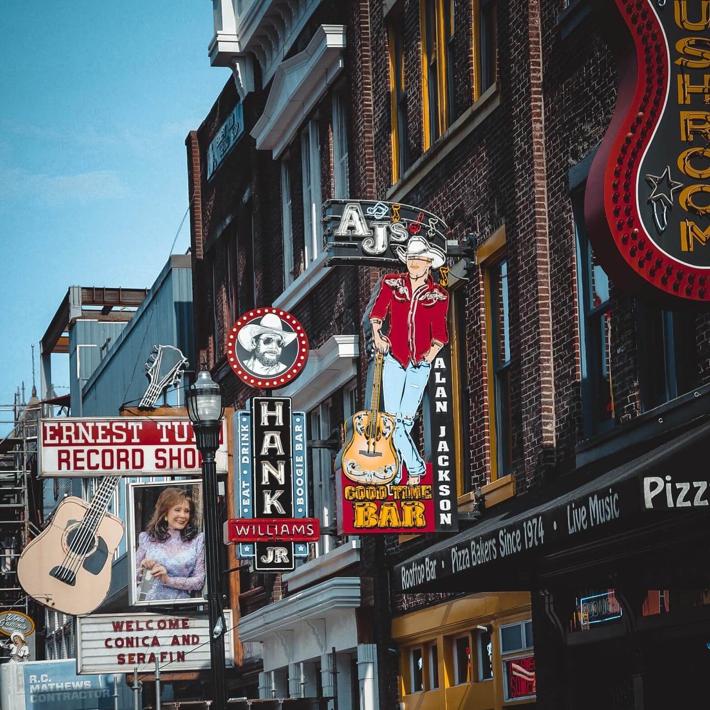 Street view of Nashville’s Lower Broadway featuring the Hank Williams Jr. Bar sign renovated by RNGD, surrounded by iconic honky-tonk venues.