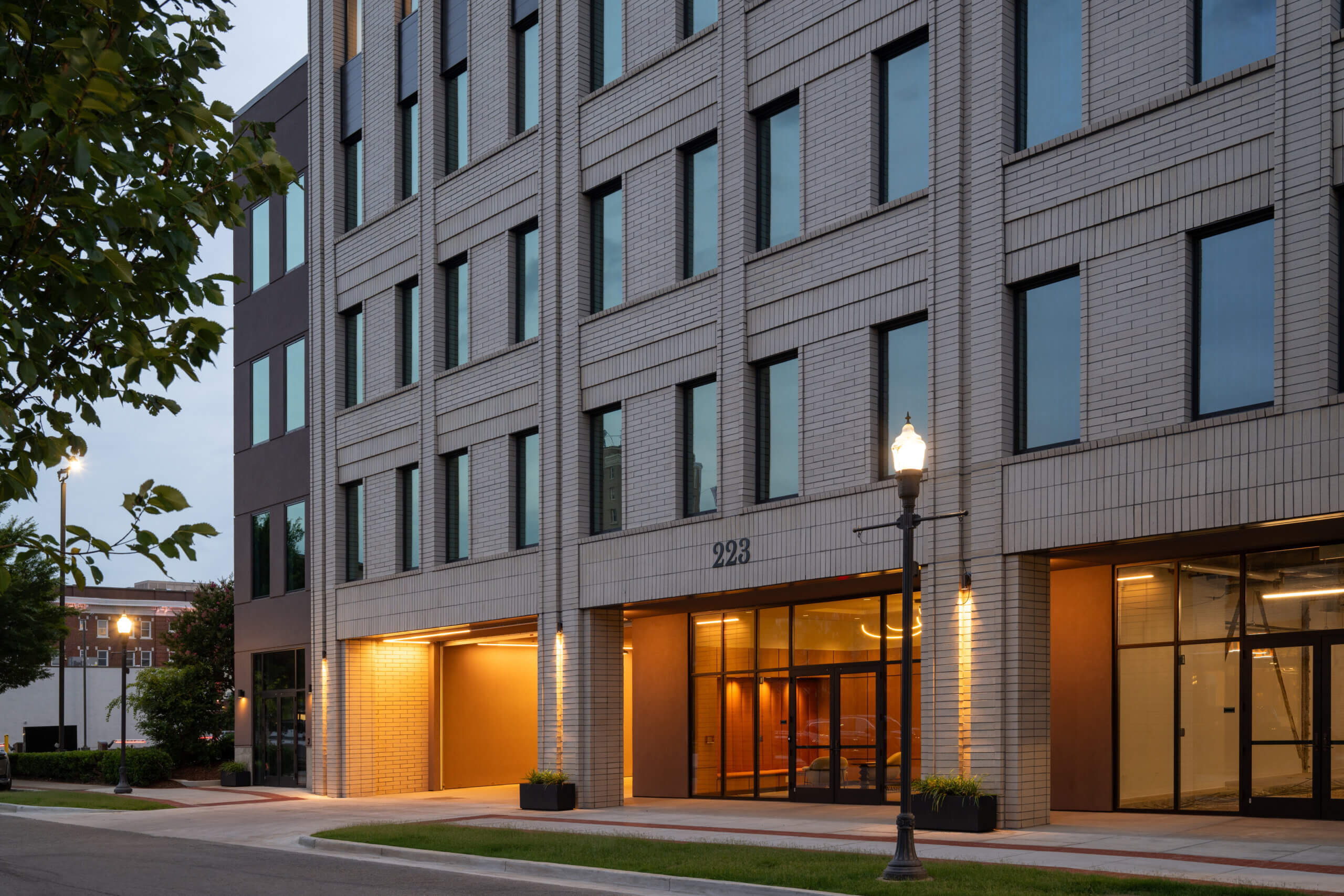 Street-level entrance of Lewter District Office at dusk with storefront retail and illuminated façade