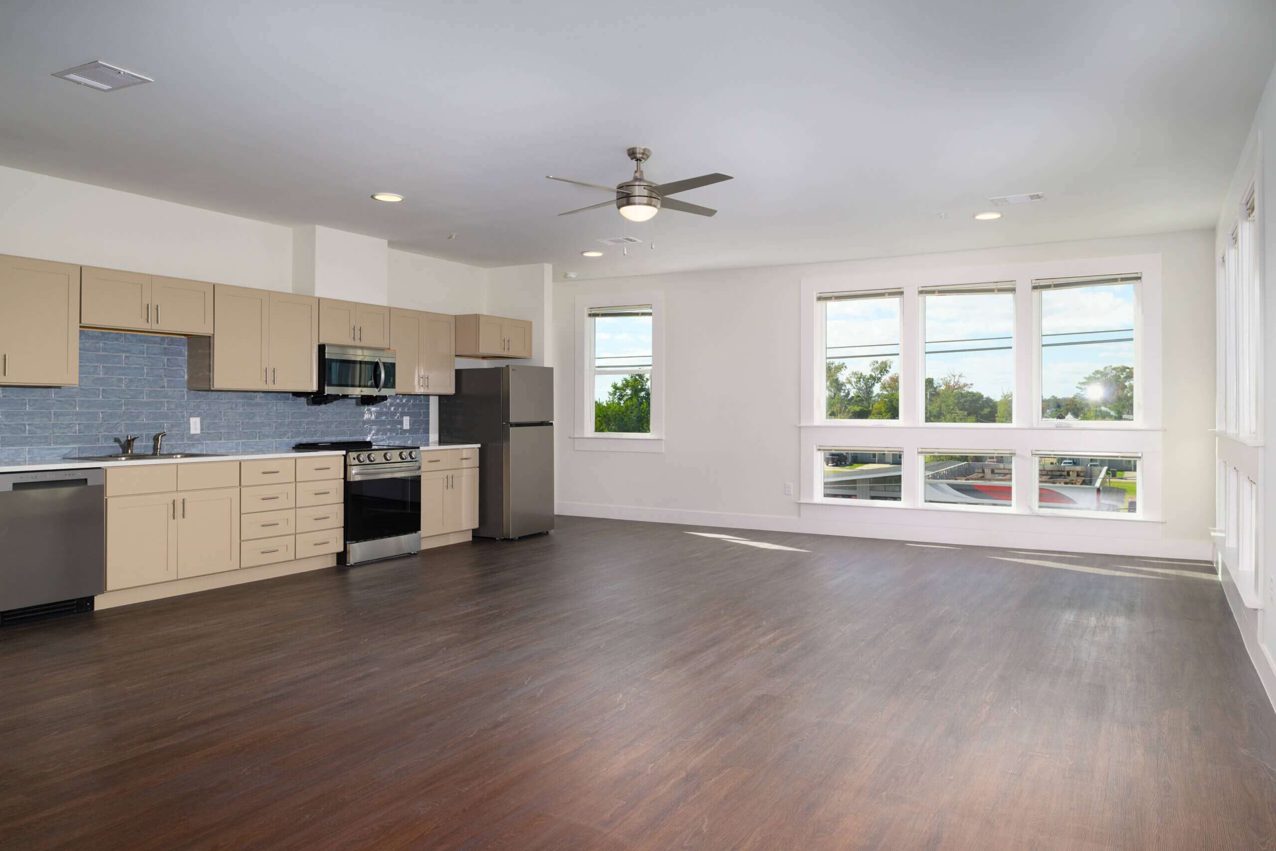 Open-plan apartment living space with kitchen and windows at Mid City Lofts