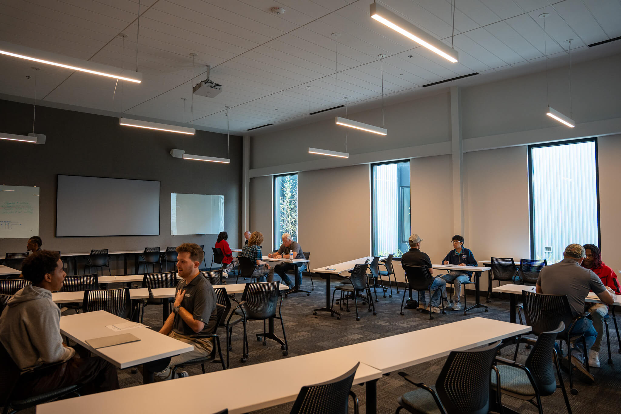 Students and RNGD team members participate in one-on-one conversations throughout a classroom during a workforce development event.