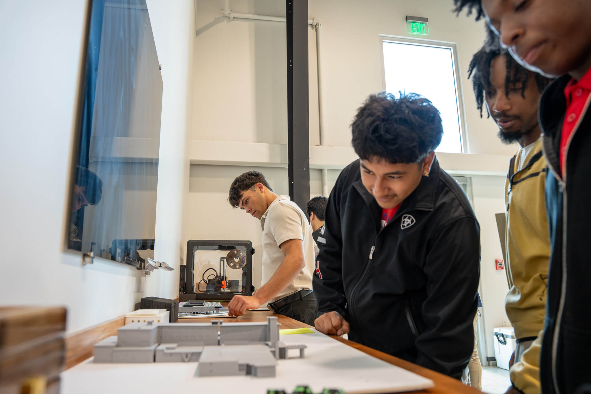 Students examine architectural models and 3D printed components during a technology and innovation demonstration at RNGD headquarters.