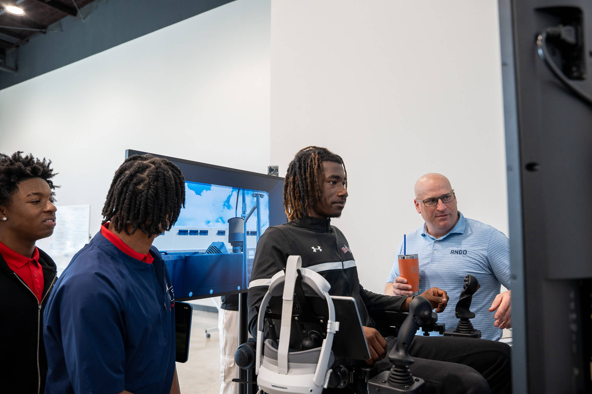 Students participate in a construction equipment simulator demonstration with guidance from an RNGD team member.