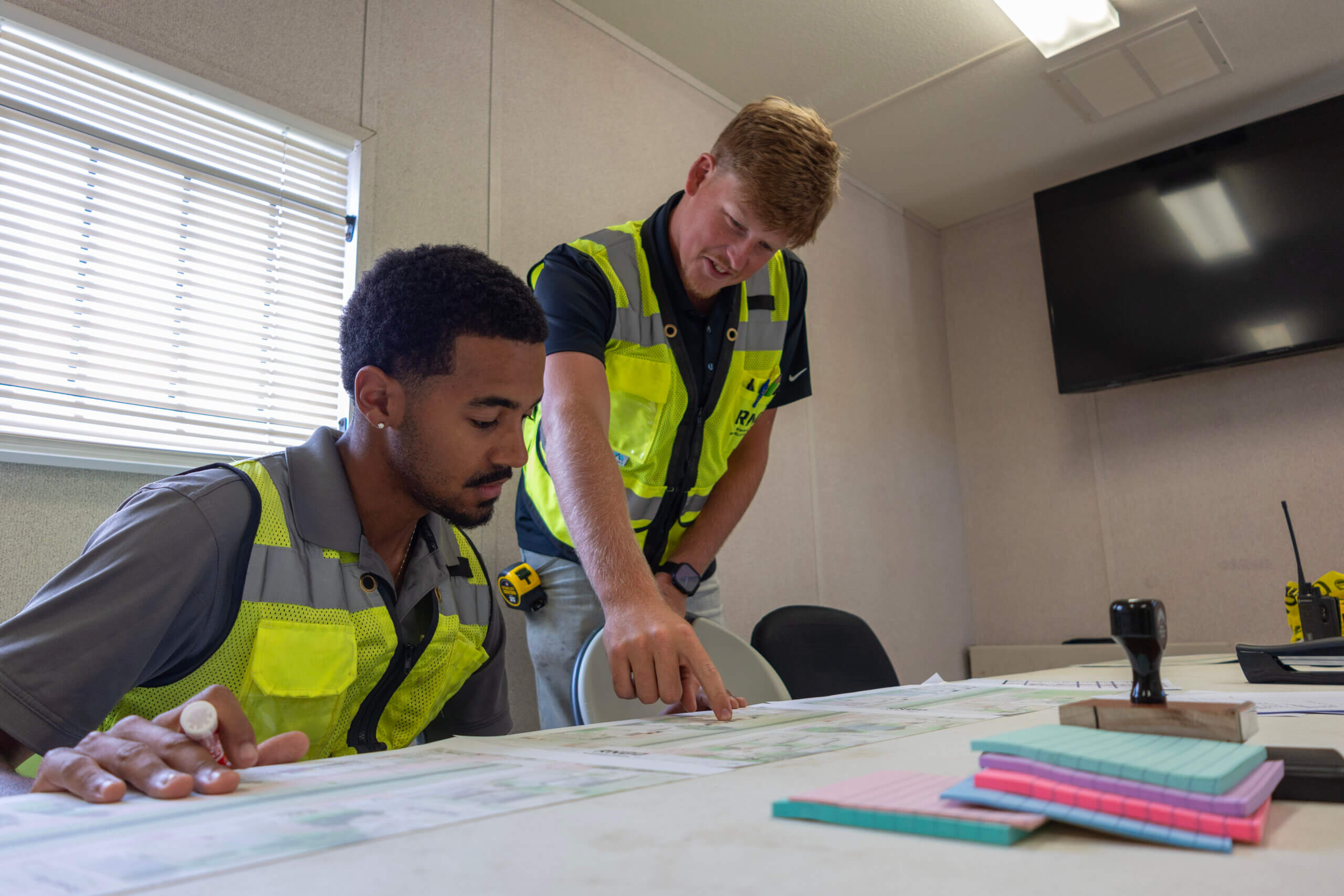 RNGD Project Engineers Isaiah Margan and Makade Penton review construction plans together inside a jobsite trailer during project coordination.