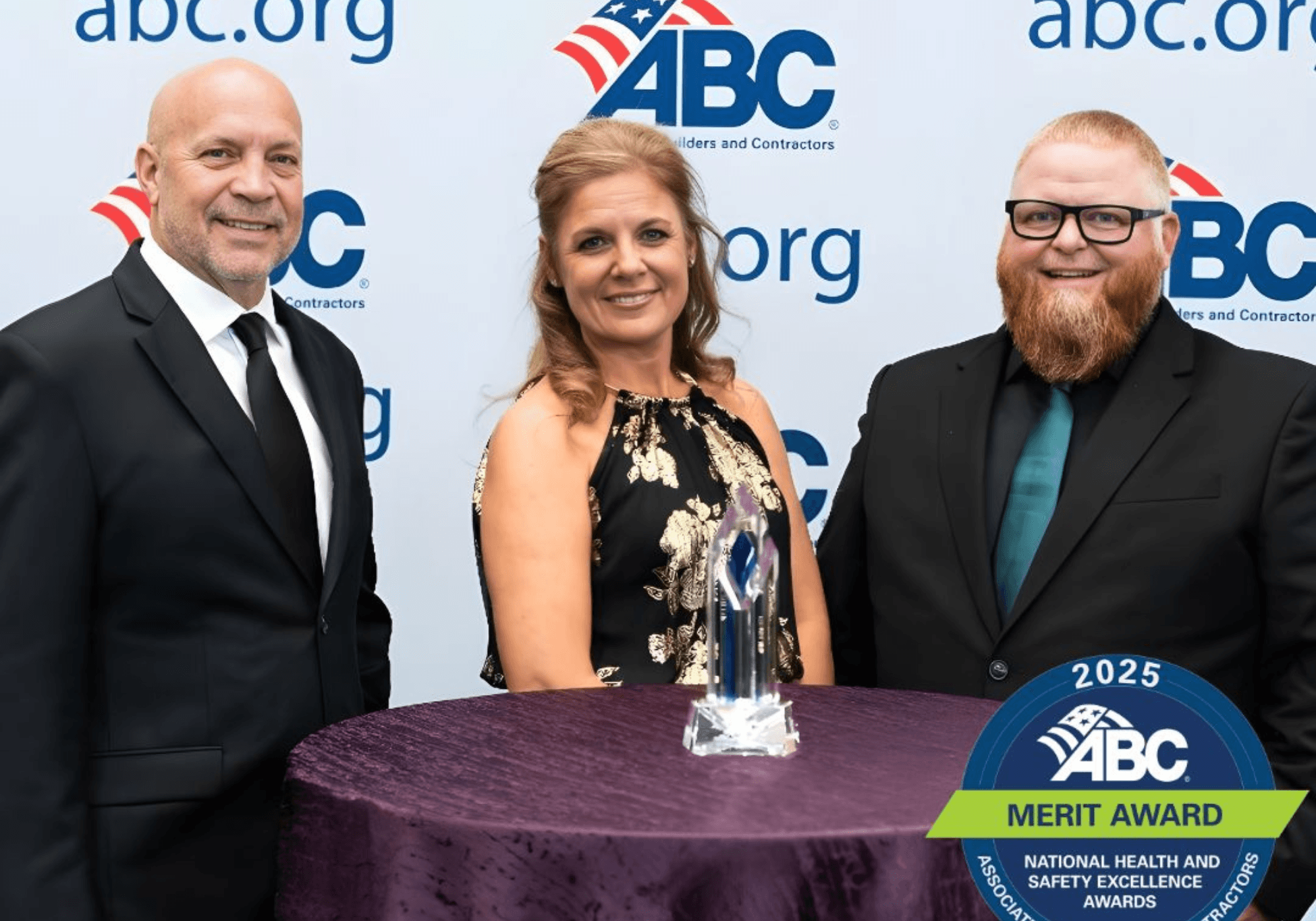 Three RNGD team members pose with the 2025 ABC Merit Award for National Health and Safety Excellence in front of an Associated Builders and Contractors backdrop.