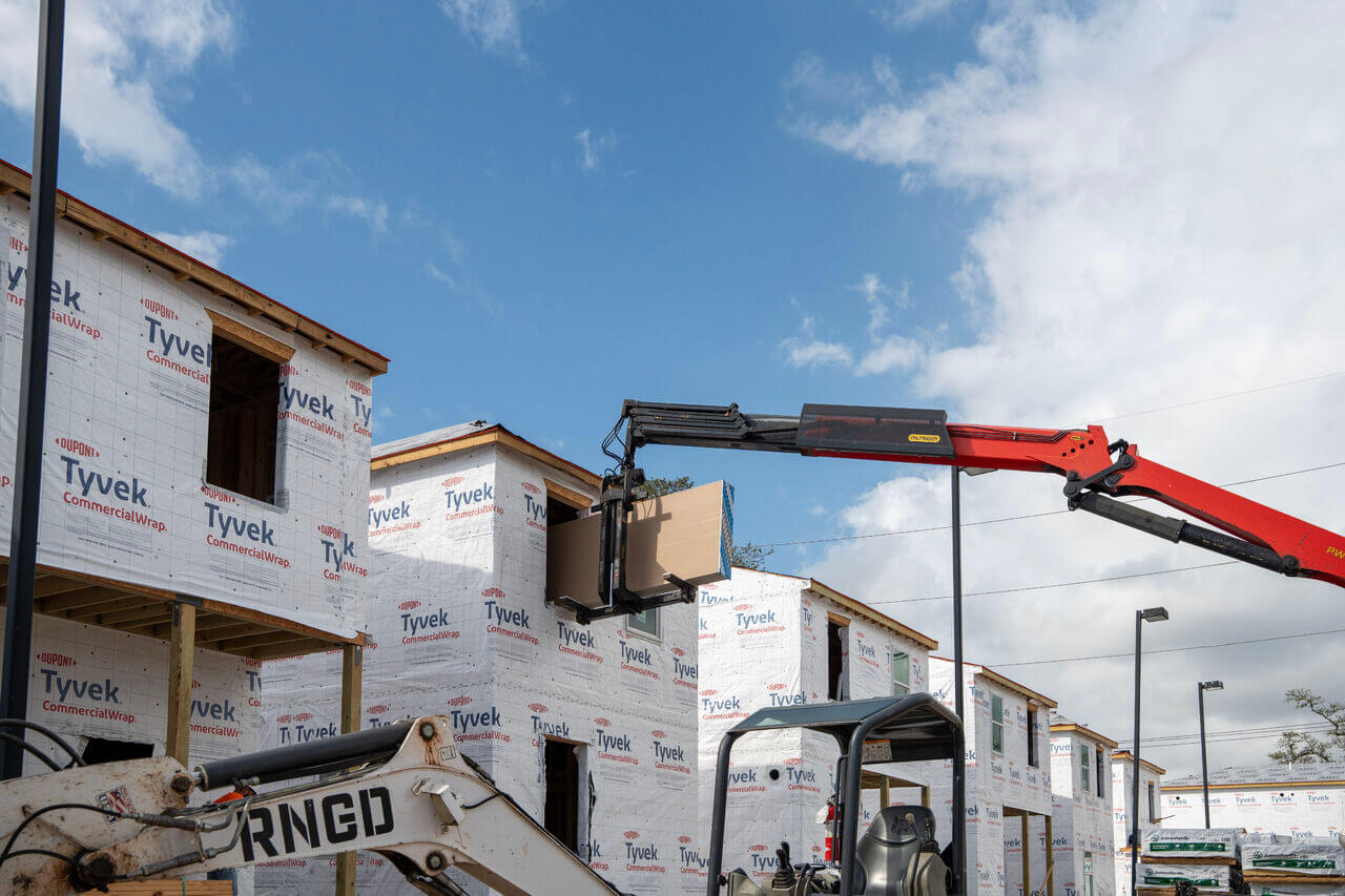 Construction equipment installing materials on framed residential units during Lafitte Phase VII construction