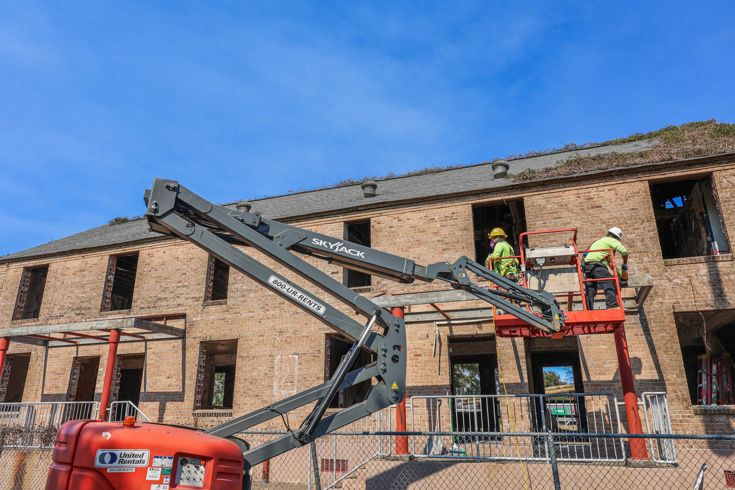 Construction crew performing exterior work on historic BW Cooper building using lift equipment
